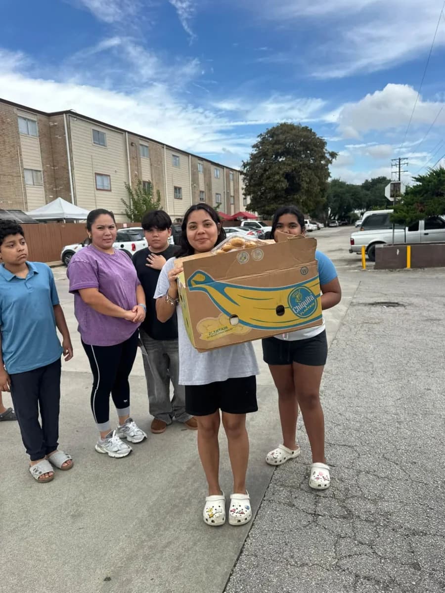 Familias recibiendo cajas de alimentos en un estacionamiento