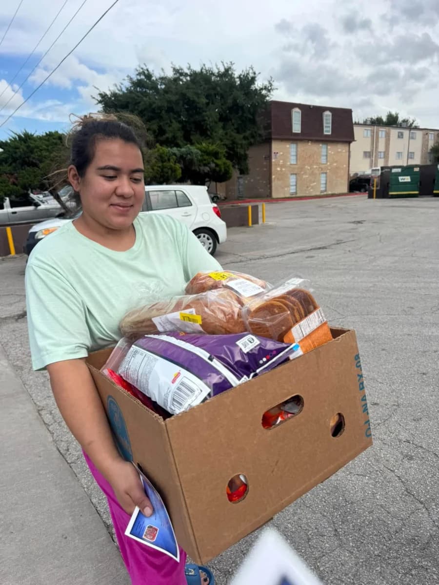 Voluntaria sonriente sosteniendo una caja de alimentos y pan